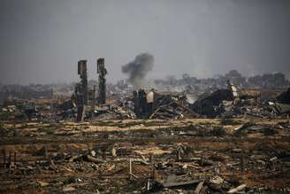 Coluna de fumaça se eleva sobre os prédios destruídos na cidade de Gaza