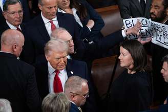 O líder da maioria na Câmara dos Representantes, Steve Scalise, bloqueia uma placa segurada pelo deputado Al Green, enquanto o presidente Donald Trump chega para seu discurso
