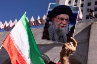 Manifestante segura foto de Khamenei em protesto contra guerra em Los Angeles, nos EUA