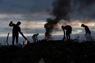 Catadores trabalham no entardecer de num aterro sanitário em Rio Branco, no Acre: estima-se que mais de um milhão de pessoas exerçam essa atividade no Brasil, que é responsável por cerca de 90% de todo o material reciclável que chega às indústrias do país.