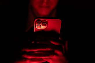 Jovem usando celular no escuro