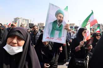 Mulher segura foto de Mojtaba Khamenei em funeral de Ali Larijani em Teerã