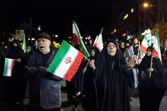 Mulher rezando com bandeira do Irã