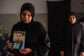 Mulher segura foto de filho morto por Israel no Líbano