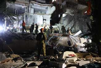 Equipes israelenses de busca e resgate trabalham no local de um prédio residencial destruído por um ataque iraniano em Haifa