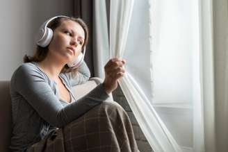 Mulher com semblante triste ouve música nos fones de ouvido