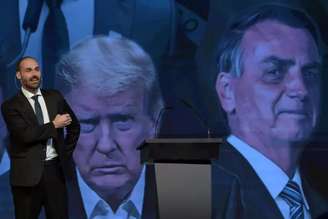 Eduardo Bolsonaro diante de uma imagem de seu pai e de Donald Trump