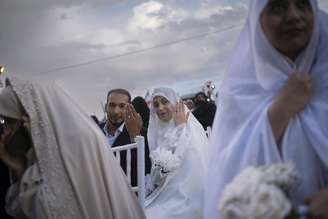 Um casal exibe suas alianças durante uma cerimônia de casamento em massa para Casais Abnegados, organizada pela Guarda Revolucionária Islâmica.