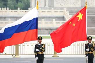 Militares seguram bandeiras da Rússia e da China durante viagem de Putin a Xi