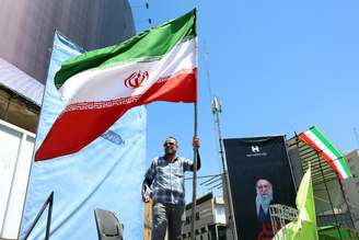 Homem segura bandeira iraniana em Teerã, capital do país