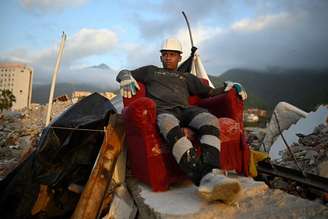 Socorrista descansa em sofá em meio a destroços de edifício que desabou em Caraballeda