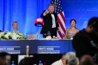 O presidente dos EUA, Donald Trump, joga seu boné TRUMP 2028 para um participante durante o Jantar dos Correspondentes da Casa Branca