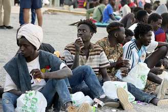 Migrantes se alimentam em ponto de distribuição de comida da Cruz Vermelha em Ceuta