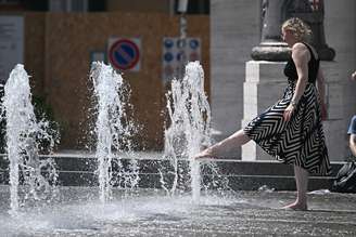 Mulher se refresca contra calor em fonte no centro de Gênova