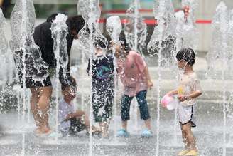 Coreanos se refrescam em fonte em Seul durante verão