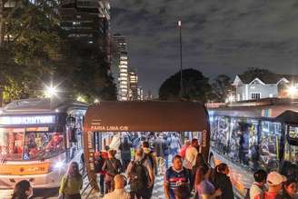 Ponto de ônibus na Av. Rebouças, próximo ao cruzamento com a Av. Brigadeiro Faria Lima. Do lado esquerdo, fachada de prédios recém-construídos e, à direita, área predominantemente ocupada por casas.