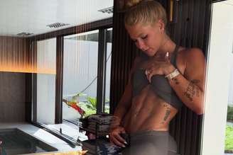 Virginia posa mostrando piercing enquanto faz exercício