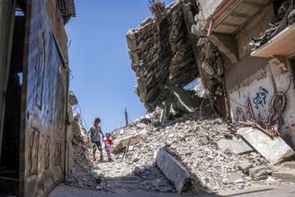 Duas crianças pelos escombros de um prédio que desabou em Khan Yunis, no sul da Faixa de Gaza