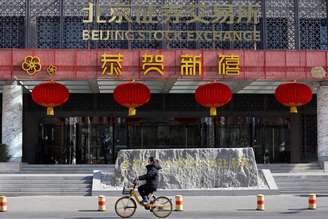 Mulher passa de bicicleta em frente ao prédio da Bolsa de Valores de Pequim, decorado com enfeites do Ano Novo Lunar, na Rua Financeira de Pequim, China, em 8 de fevereiro de 2024
REUTERS/Florence Lo