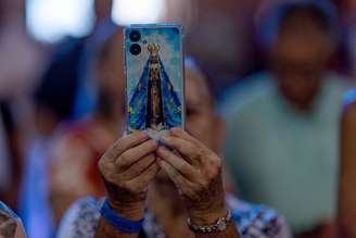 Mulher segura imagem de Nossa Senhora no Santuário Nacional de Aparecida (SP)