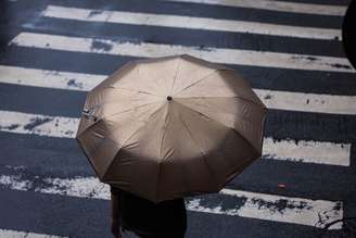 Pedestres enfrentam a chuva com seus guarda-chuvas e capas nas esquinas da Rua Joaquim Antunes e Arthur de Azevedo, no bairro de Pinheiros, zona oeste da cidade.