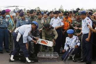 Militares indonésios carregam caixa-preta do voo 8501 da AirAsia na base aérea de Pangkalan Bun, após o equipamento ser retirado do mar e levado a terra