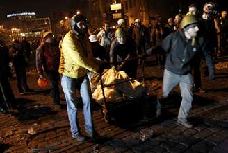 Manifestantes antigoverno empurram carrinho com sacolas cheias de pedras para construer barricadas no centro de Kiev