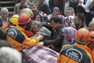 <p>Turcos se emocionam enquanto agentes do resgate retiram um mineiro ferido após a explosão em uma mina, em Soma, na Turquia, em 14 de maio</p>