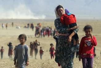 Mulheres e crianças yazidis caminham para fronteira do Iraque