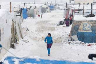 <p>Uma refugiada síria caminha sobre a neve em um acampamento de Bar Elias, no vale de Bekaa, Líbano, em janeiro de 2015</p>