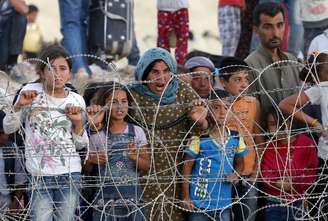 Sírios curdos de Kobani aguardam atrás de cerca para cruzar fronteira com Turquia.  25/6/2015.