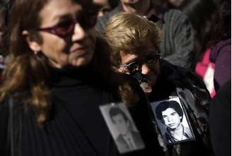 Mulheres com fotos de desaparecidos assistem a um ato em homenagem às vítimas do Golpe de Estado de 1973.
