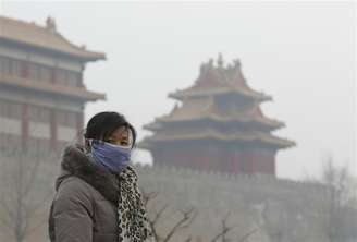Visitante usa máscara do lado de fora da Cidade Proibida em dia enevoado no centro de Pequim. Qualidade do ar em Pequim foi a "pior já registrada" no sábado e domingo, segundo ambientalistas, enquanto o centro de monitoramento da poluição da cidade advertia os moradores a permanecerem dentro de casa. 13/01/2013