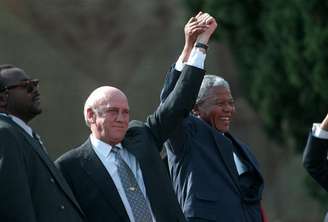 <p>Nelson Mandela (à direita) e o segundo ex-vice-presidente sul-africano F.W. De Klerk (centro) acenam para uma multidão após a posse presidencial, em maio de 1994</p>