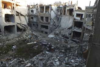 Civil caminha em meio aos escombros de prédios atingidos durante confronto entre rebeldes e forças do governo, em Homs. 