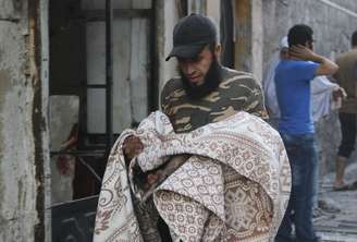 Homem carrega um corpo de vítima da violência na cidade de Aleppo, na Síria, nesta segunda-feira