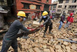 Voluntários ajudam a remover destroços de casa destruída por terremoto em Katmandu