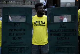Manifestante com camiseta da Anistia Internacional protesta no aniversário de 50 anos do golpe de 1964, ao lado de um escudo com os dizeres "1975 - Assassinato de Vladimir Herzog"
01/04/2014
REUTERS/Pilar Olivares
