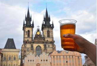 Homem segura copo de cerveja ao longo da cidade de Praga