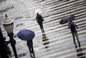 Pedestres se protegem da chuva na região central de São Paulo, na tarde de 31 de março