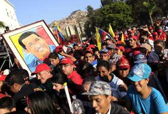 Com imagens do ex-mandatário e bandeira, os simpatizantes de Chávez esperam para se despedir