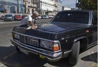 Limusines que serviram a Fidel Castro foram transformadas em táxis em Havana, capital de Cuba. Na imagem, motorista Moises Suarez limpa um modelo soviético que já pertenceu ao ditador cubano