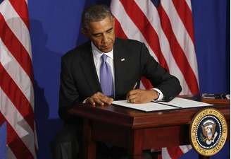 <p>O presidente dos EUA, Barack Obama, assina uma ordem executiva para reforçar a segurança dos cartões de crédito, em Washington, em 17 de outubro</p>