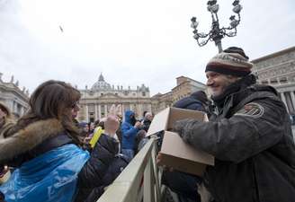 Mauro Casubolo, um sem-teto de Roma, entrega um Evangelho de bolso a uma fiel na Praça de São Pedro, após a oração do Angelus conduzida pelo papa Francisco