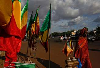 Mulher anda ao lado de bandeiras do Mali