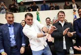 Derrite e Tarcísio observam Flávio Bolsonaro fazer um gesto em alusão a um jogo de videogame
