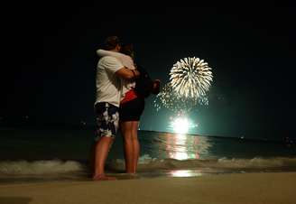<p><strong>Estados Unidos - </strong>Casal se abraça enquanto fogos de artifício marcam a entrada do Ano-Novo em praia de Honolulu, no Havaí. Este Estado americano é uma das últimas regiões do mundo a celebrar o Réveillon</p>