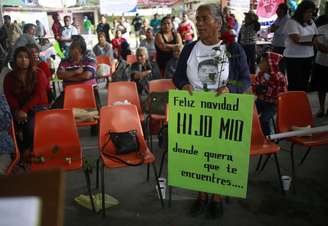 Mãe de estudante desaparecido segura cartaz com a mensagem "Feliz Natal, meu filho. Aonde quer que você esteja"