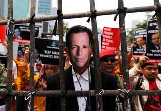 Um homem usando uma máscara do primeiro-ministro australiano, Tony Abbott, se posiciona atrás de uma grade de bambu durante protesto de estudantes contra o premiê, em Jacarta, na Indonésia, nesta quarta-feira. 25/02/2015