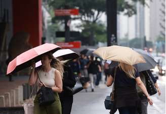 Pedestres caminham com guarda-chuva em tarde chuvosa na Avenida Paulista.